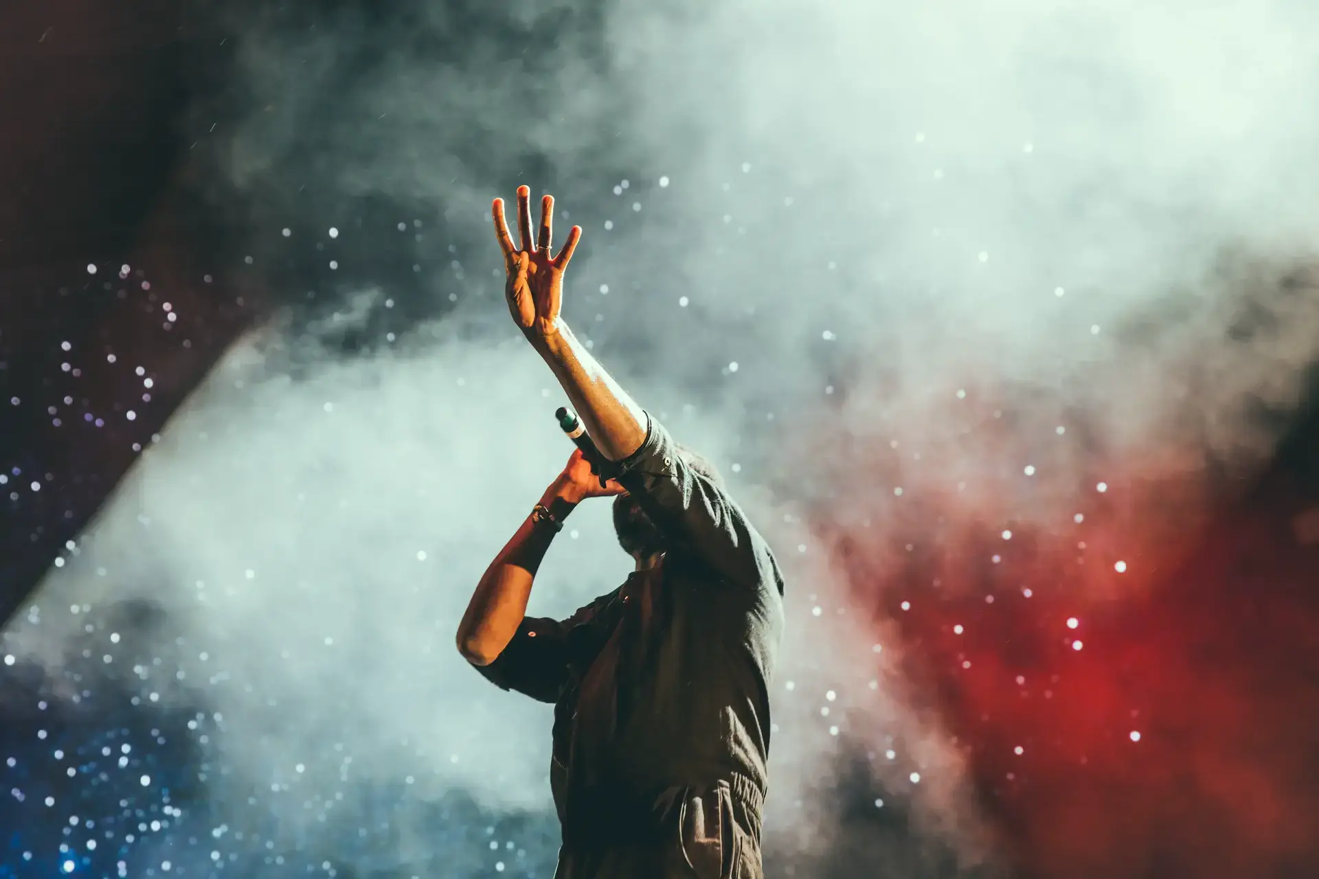 Photo du chanteur d'un concert faisant le signe quatre avec sa main