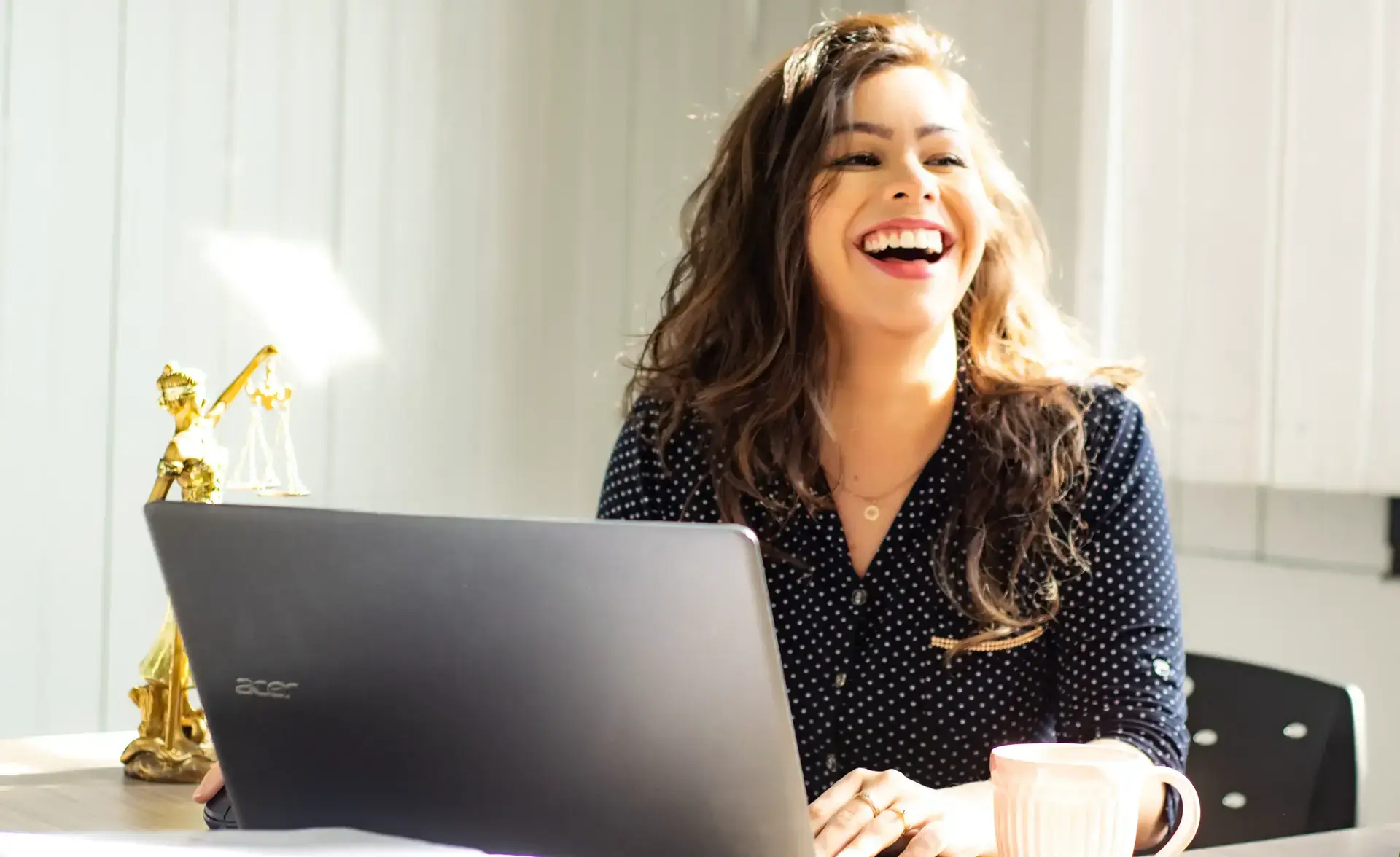 Photo d'une employée devant son ordinateur entrain de rire